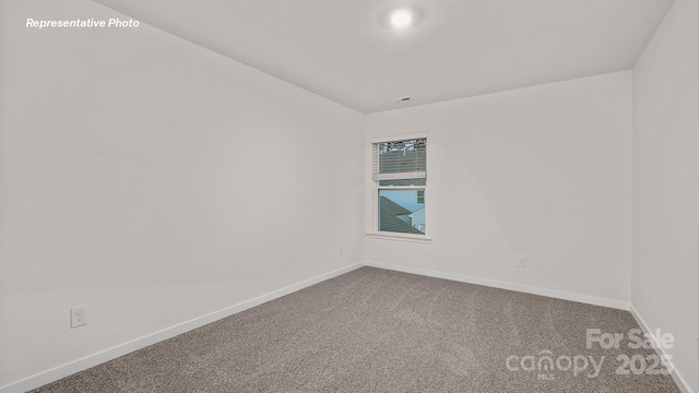 carpeted empty room featuring baseboards