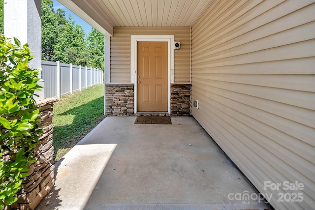 entrance to property with fence and stone siding