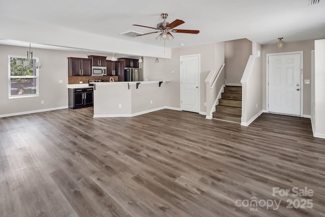 unfurnished living room with baseboards, dark wood-style floors, and stairs