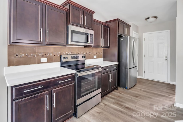 kitchen featuring light countertops, stainless steel appliances, tasteful backsplash, and light wood-type flooring