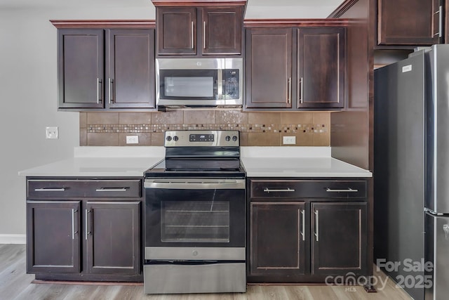 kitchen with light countertops, appliances with stainless steel finishes, decorative backsplash, and light wood-style flooring