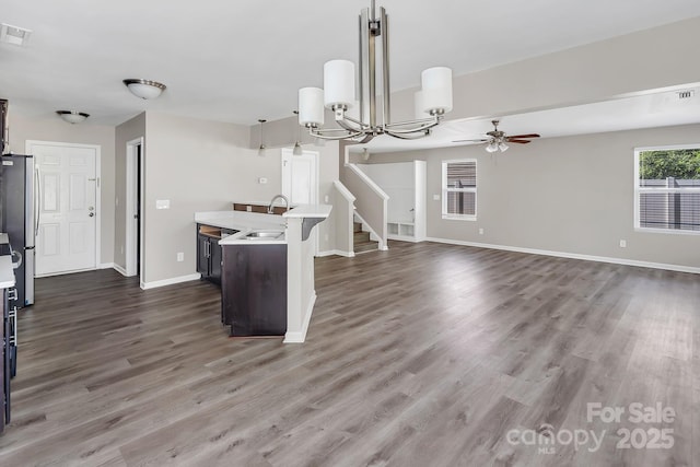 kitchen with freestanding refrigerator, a sink, ceiling fan with notable chandelier, and light countertops
