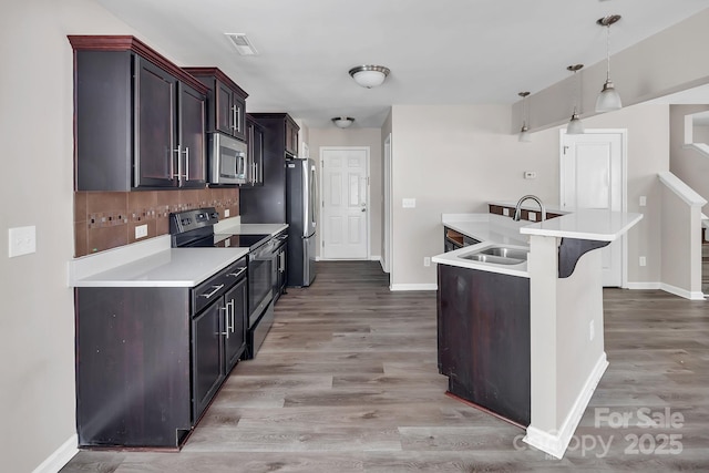 kitchen with a sink, baseboards, stainless steel appliances, and light countertops