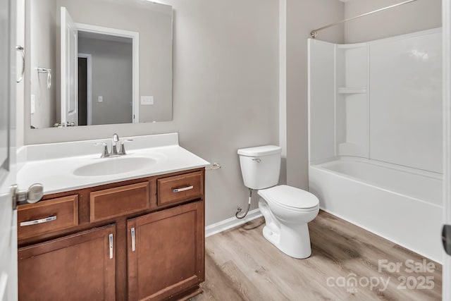 bathroom featuring vanity, wood finished floors, toilet, baseboards, and washtub / shower combination