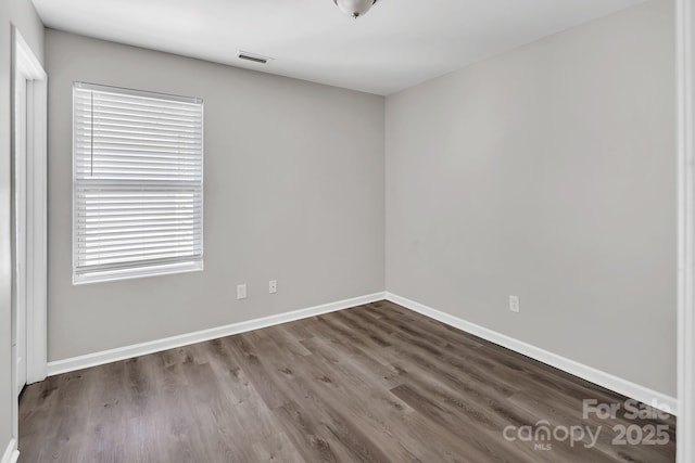 unfurnished room with baseboards, wood finished floors, and visible vents