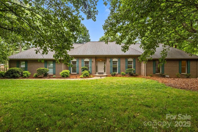 ranch-style house with brick siding, a front lawn, and roof with shingles