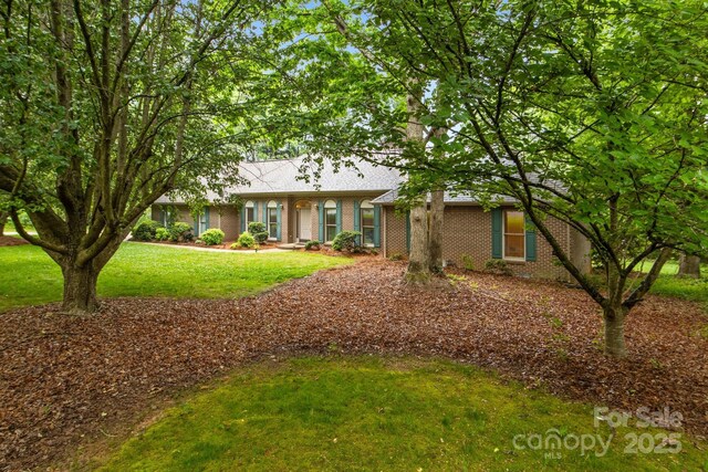 ranch-style house with brick siding, roof with shingles, and a front lawn