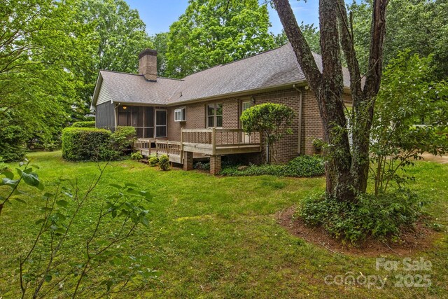 rear view of house with a yard, brick siding, a chimney, and a wooden deck
