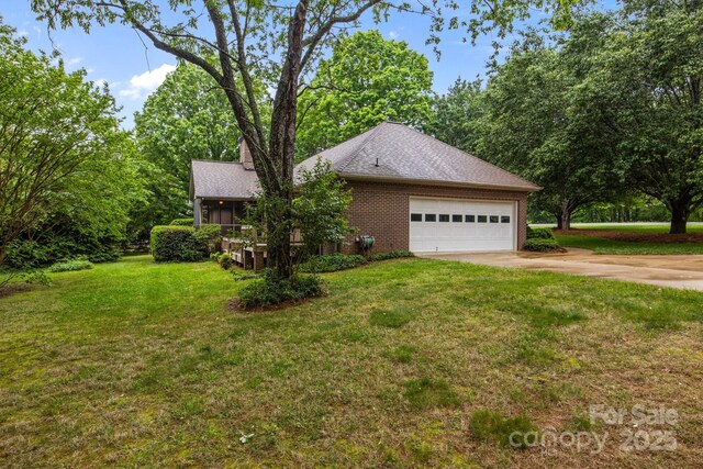 view of home's exterior with a lawn, an attached garage, driveway, and brick siding