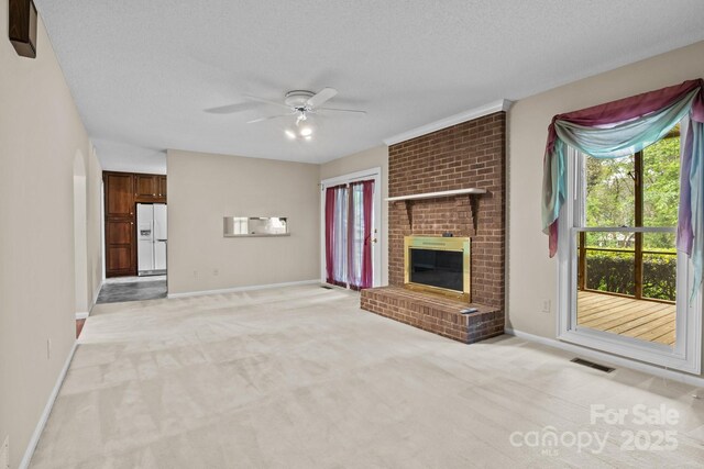 unfurnished living room featuring visible vents, a brick fireplace, light carpet, baseboards, and a ceiling fan