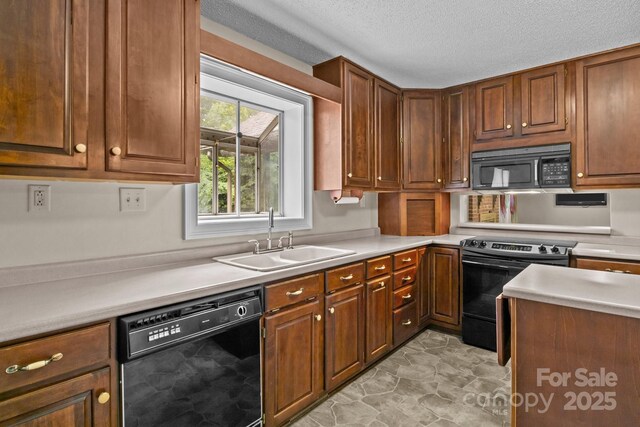 kitchen featuring a textured ceiling, brown cabinets, a sink, light countertops, and black appliances