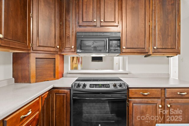 kitchen featuring black microwave, light countertops, brown cabinetry, and range with electric cooktop