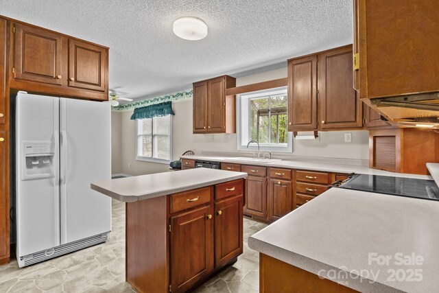 kitchen featuring light countertops, a sink, a wealth of natural light, and white refrigerator with ice dispenser