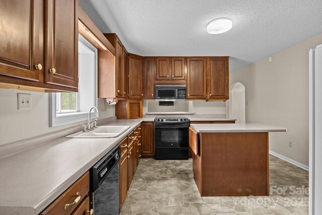 kitchen with a sink, light countertops, a textured ceiling, a kitchen island, and black appliances
