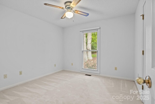 carpeted empty room featuring visible vents, a textured ceiling, baseboards, and ceiling fan
