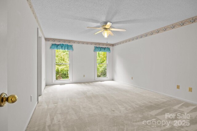 spare room with carpet floors, baseboards, a ceiling fan, and a textured ceiling