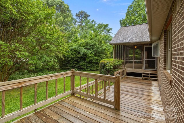 deck with a lawn and a sunroom