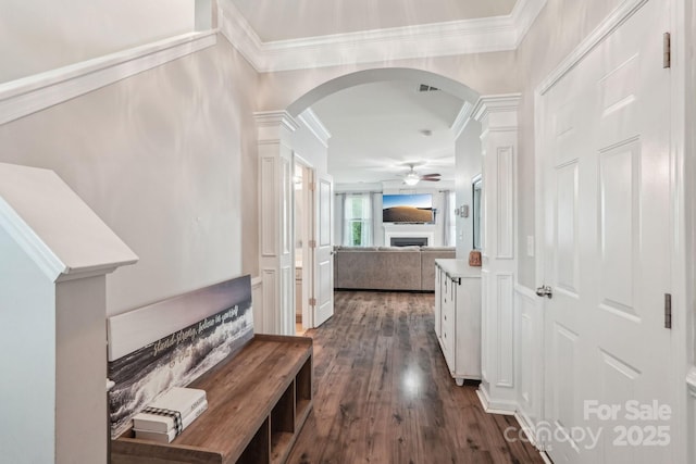 hallway featuring dark wood-style floors, decorative columns, arched walkways, and ornamental molding