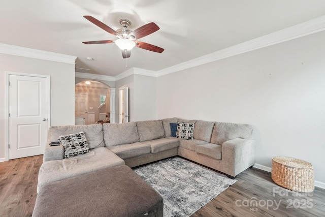 living area featuring arched walkways, ceiling fan, wood finished floors, and crown molding