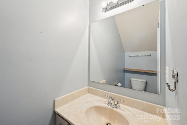 bathroom with toilet, vaulted ceiling, and vanity