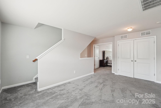unfurnished living room with carpet, visible vents, and baseboards