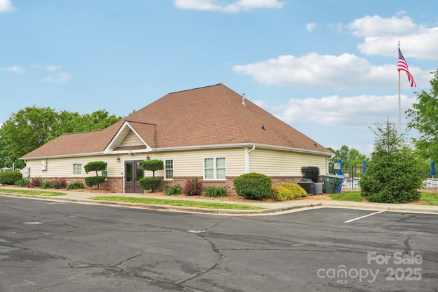 exterior space featuring central AC, uncovered parking, and brick siding
