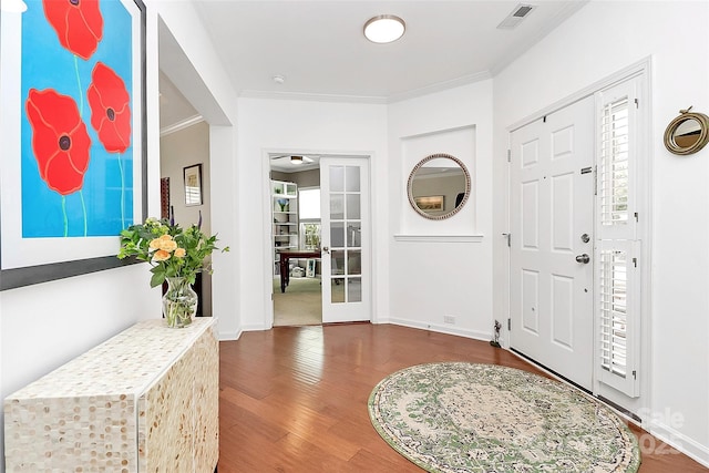 foyer entrance featuring crown molding, visible vents, plenty of natural light, and wood finished floors
