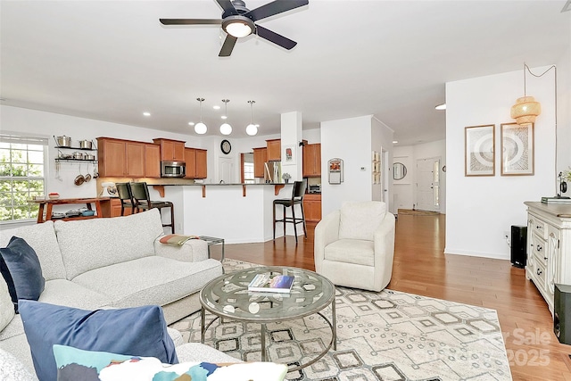 living room featuring recessed lighting, baseboards, a ceiling fan, and light wood-type flooring
