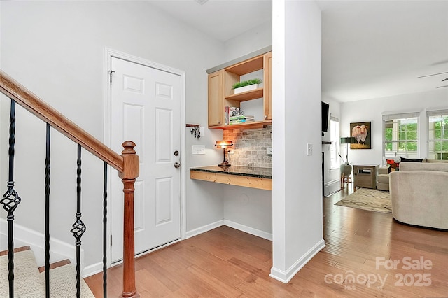 entrance foyer featuring stairs, baseboards, and light wood finished floors