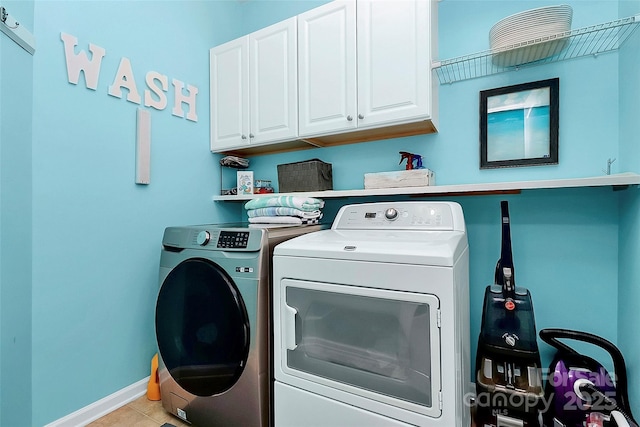 clothes washing area with separate washer and dryer, cabinet space, baseboards, and light tile patterned flooring