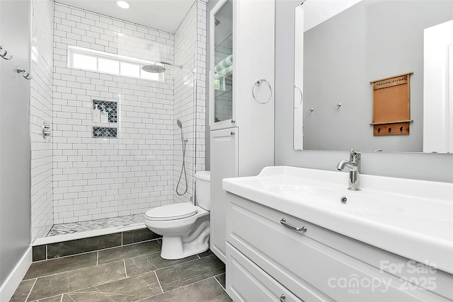 full bathroom featuring vanity, toilet, baseboards, tiled shower, and recessed lighting