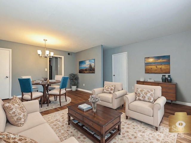 living area featuring baseboards, visible vents, wood finished floors, and a notable chandelier