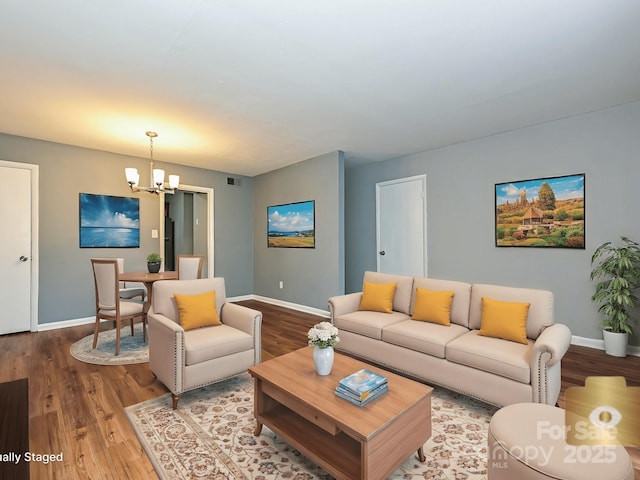living room with baseboards, wood finished floors, a notable chandelier, and visible vents