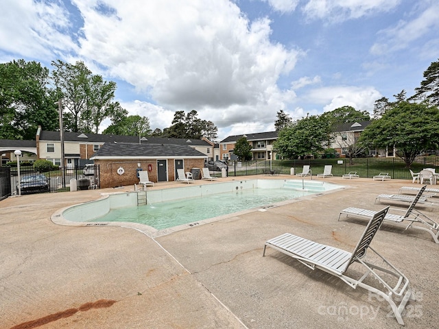 community pool with a patio area and fence