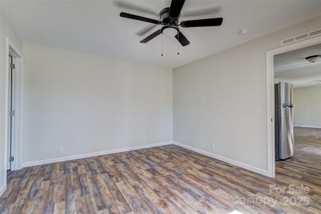 unfurnished room with ceiling fan, visible vents, baseboards, a textured ceiling, and wood finished floors