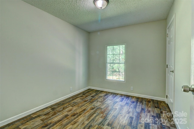 empty room featuring dark wood-type flooring, baseboards, and a textured ceiling