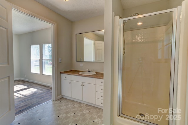 bathroom featuring tile patterned floors, a textured ceiling, vanity, and a stall shower