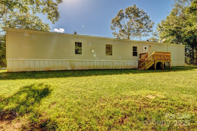 back of house with stairway, a wooden deck, and a lawn