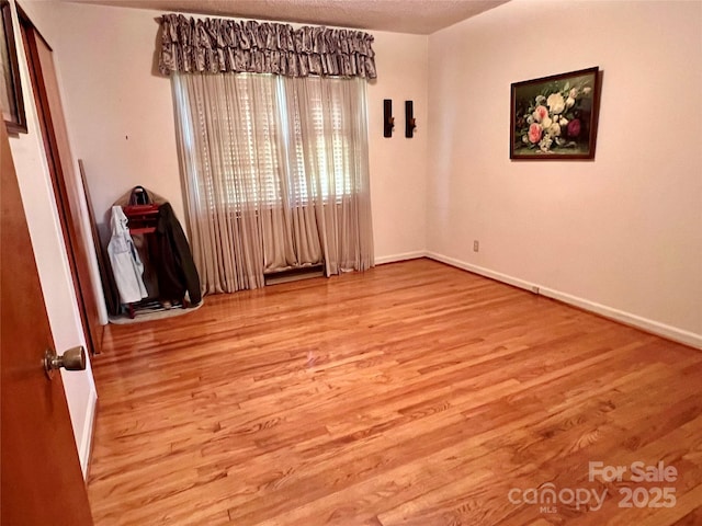 spare room with baseboards and wood finished floors