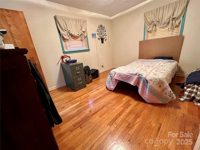 bedroom featuring baseboards, a textured ceiling, and wood finished floors