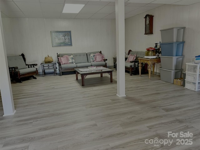 living area featuring a paneled ceiling and wood finished floors