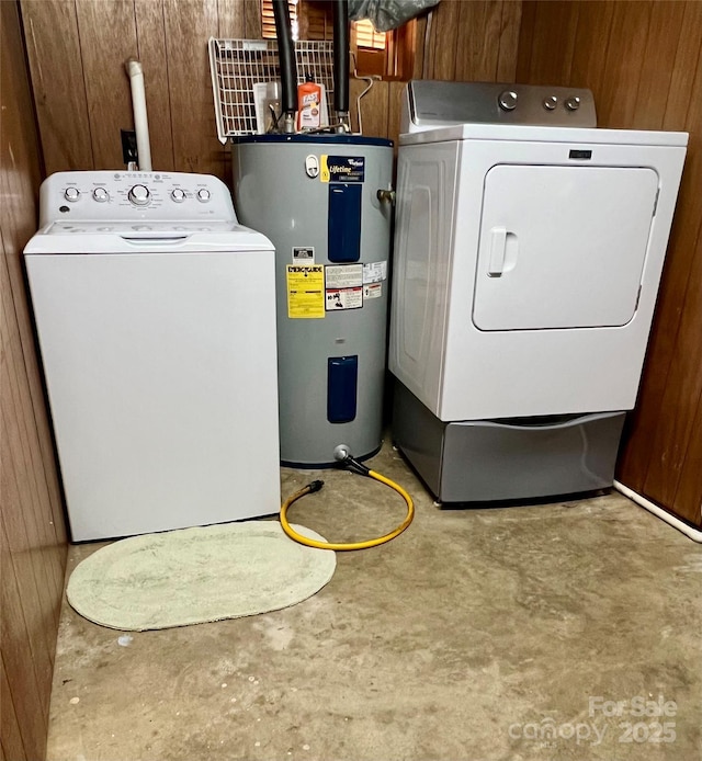 laundry area featuring laundry area, washing machine and dryer, wood walls, and electric water heater