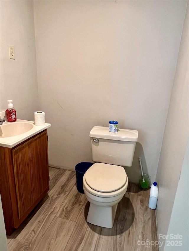 half bath with vanity, toilet, and wood finished floors