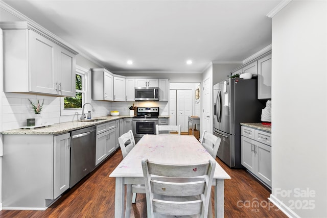 kitchen featuring decorative backsplash, ornamental molding, a sink, gray cabinetry, and stainless steel appliances