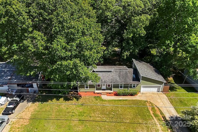 view of front of house with a shingled roof, a front lawn, and concrete driveway