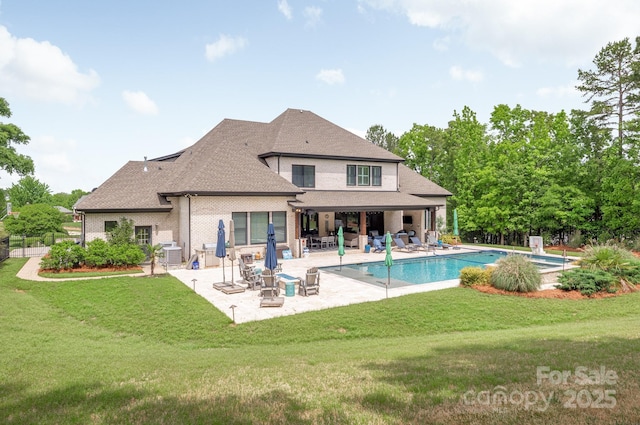 rear view of house with a patio, roof with shingles, an outdoor pool, and a lawn