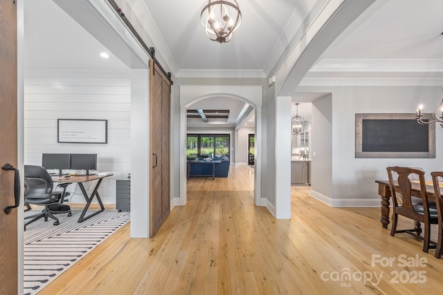 entryway with baseboards, light wood-type flooring, arched walkways, and an inviting chandelier