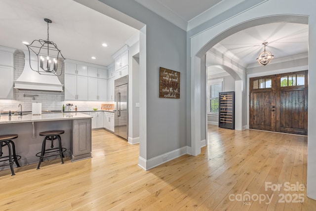 foyer entrance with ornamental molding, arched walkways, an inviting chandelier, and baseboards