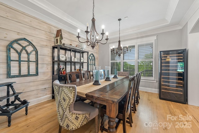 dining area with a chandelier, baseboards, light wood-style flooring, and wine cooler