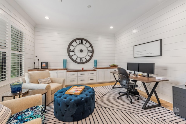 home office with wooden walls, light wood-style flooring, and a wealth of natural light